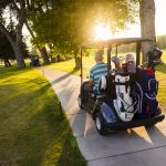 golfers riding off down a cart path in the sunset at buffalo golf club