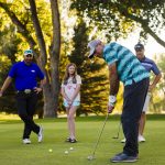 veterans putting with family members on a green