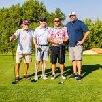 team of golfers holding their golf clubs on a fairway during a charity golf tournament in Colorado