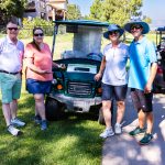 group of golfers standing next to a golf cart during a charity golf tournament in Colorado