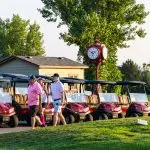 golfers walking past golf carts that are lined up for a charity tournament in Colorado
