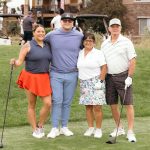 a group of golfers standing on a putting green during a charity golf tournament