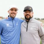 two golfers standing together smiling to start a charity golf tournament