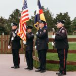 law enforcement officers with the colorado and american flag in the background during a charity golf tournament 